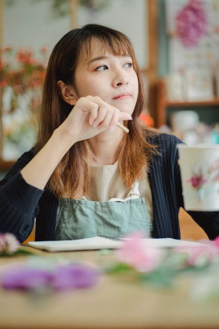 A close-up of a florist at Alperton flower shop near Alperton station Brent, arranging a bouquet of fresh flowers. The flowers include vibrant pink roses, pale peach chrysanthemums, and deep purple ir