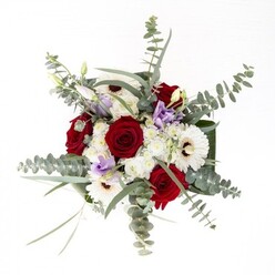 From a Brent florist's perspective, this bouquet encapsulates a subtle yet confident artistry, echoing the borough's blend of contemporary life and green spaces. Spiraled red roses hold court at the center, exuding lasting affection and warmth, while the petal-rich white gerberas, each with a distinctive brown center, offer a luminous steadiness much like the peaceful moments found in Roundwood Park. The bouquet's mood is elevated by the wispy grace of eucalyptus, its cool, silvery-green leaves catching daylight, and hints of pastel purple lisianthus evoking springtime walks along the Grand Union Canal. Alongside, fluffy clusters of white chrysanthemums and filler flowers nestle in, enhancing both texture and fullness. All are framed and gathered by deep green, broad foliage, their form providing elegant structure around the fresh stems visible in the vase. The air is faintly scented with fresh rose and clean eucalyptus, inviting feelings of renewal, comfort, and joy. Whether shared for milestones, sent in sympathy, or admired as a centrepiece in a North Wembley home, this arrangement radiates the care and attention put into every Brent delivery.